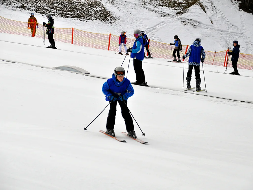 Skifahrer üben nebeneinander auf dem flachen Hang.